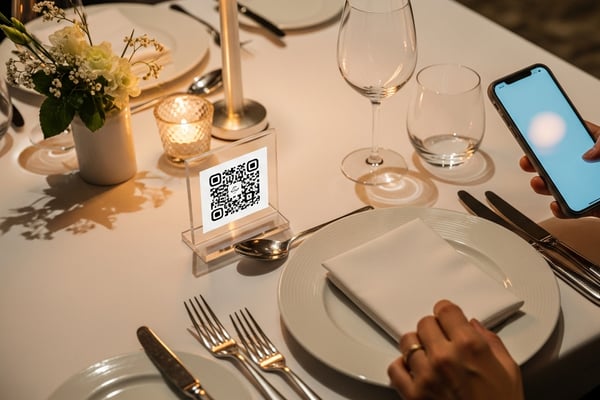 Un cliente acerca el móvil a un soporte con código QR en la mesa.